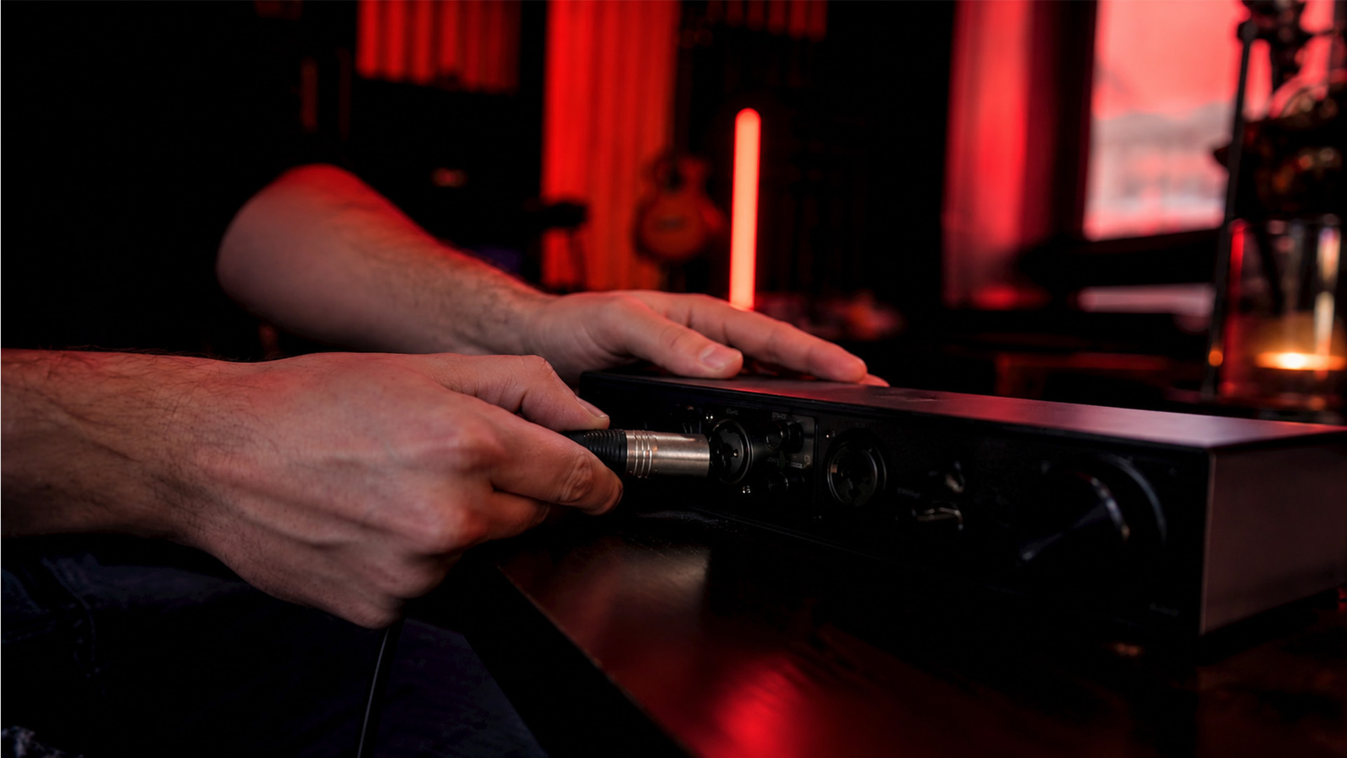 Hands connecting an audio cable in a music studio