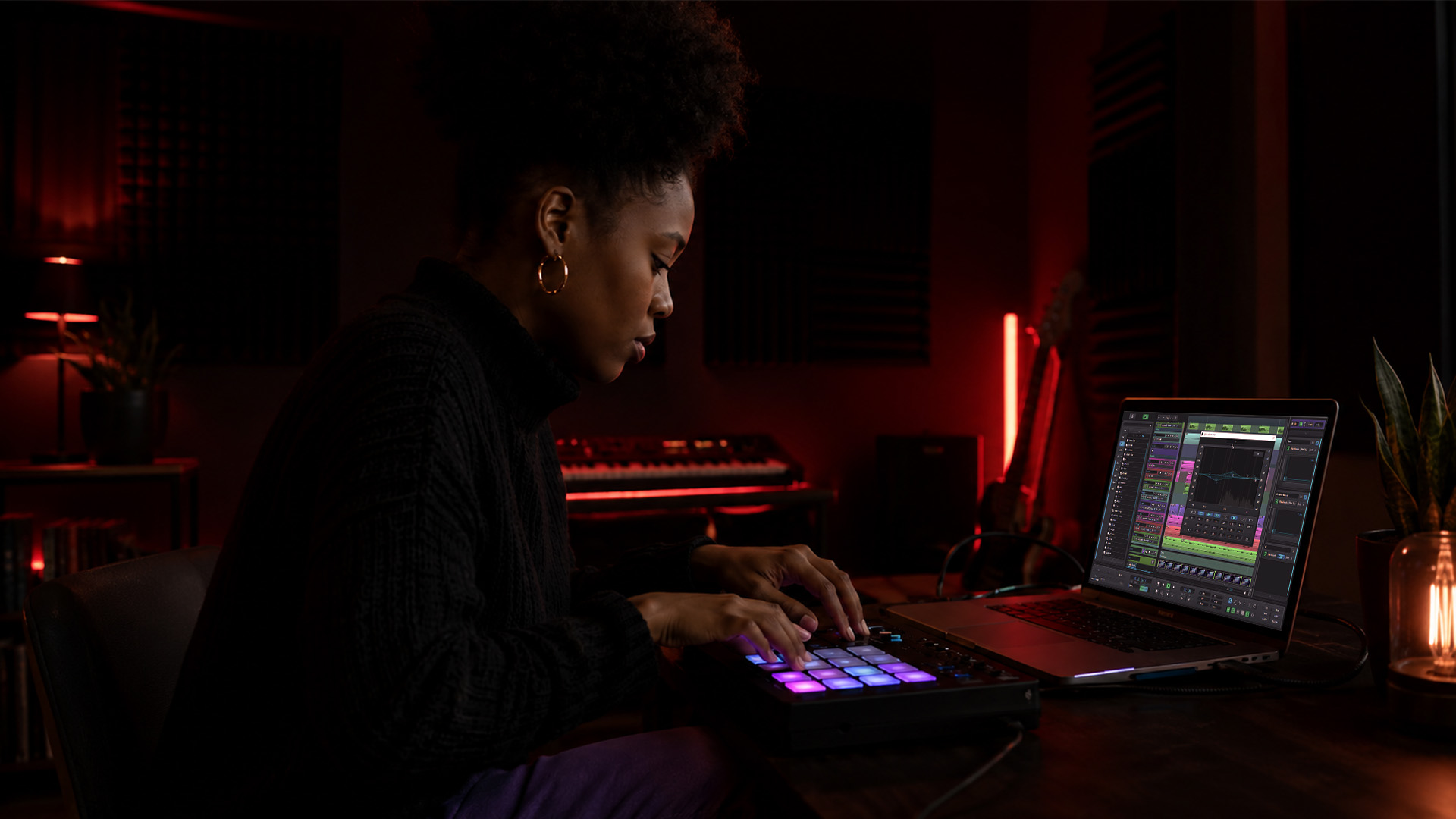 Hands using a MIDI pad and laptop in a home studio