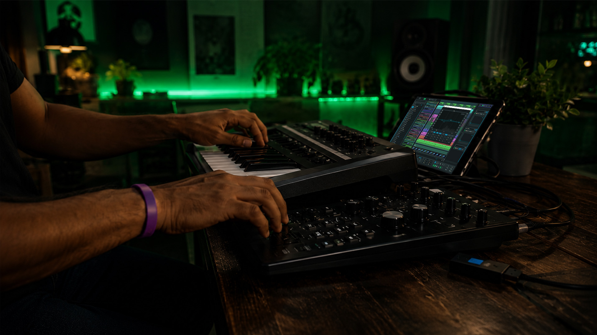 Hands operating a DAW controller and keyboard in a studio