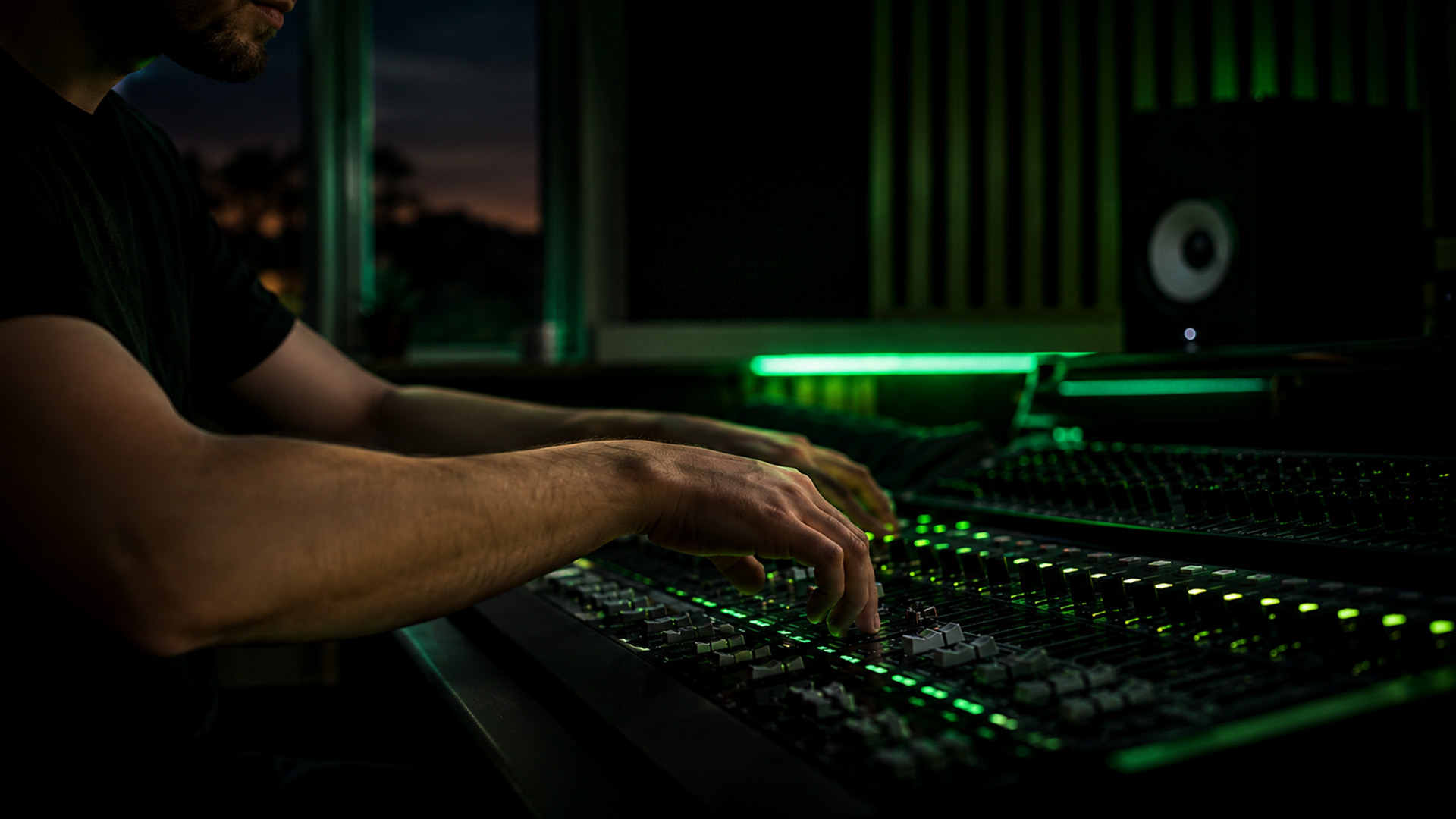 Hands adjusting mixing console knobs in a studio