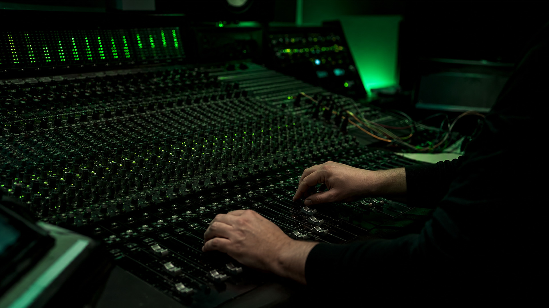 Hands on a mixing console in a professional studio