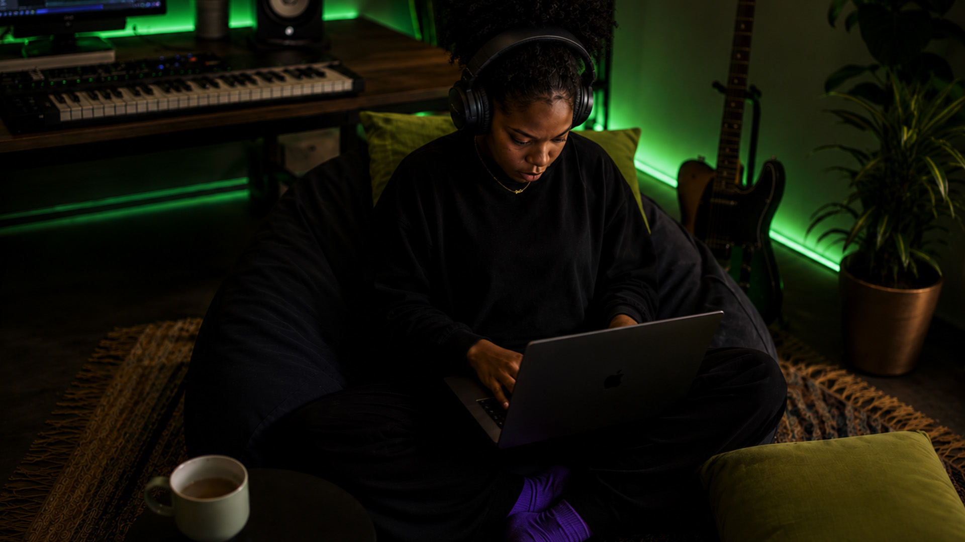 A music producer editing a MIDI piano roll at a home studio