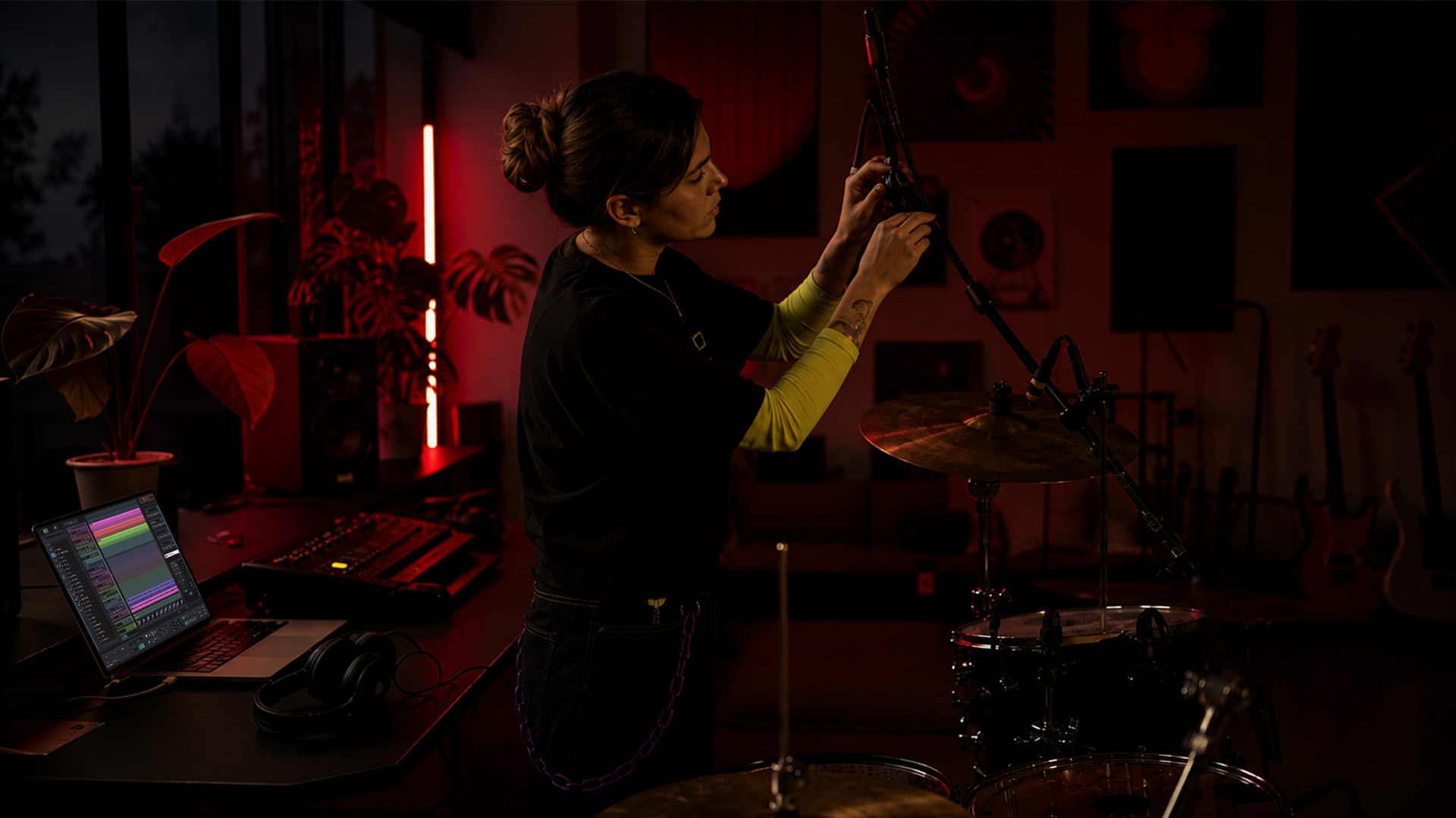 A producer adjusting drum overhead microphones