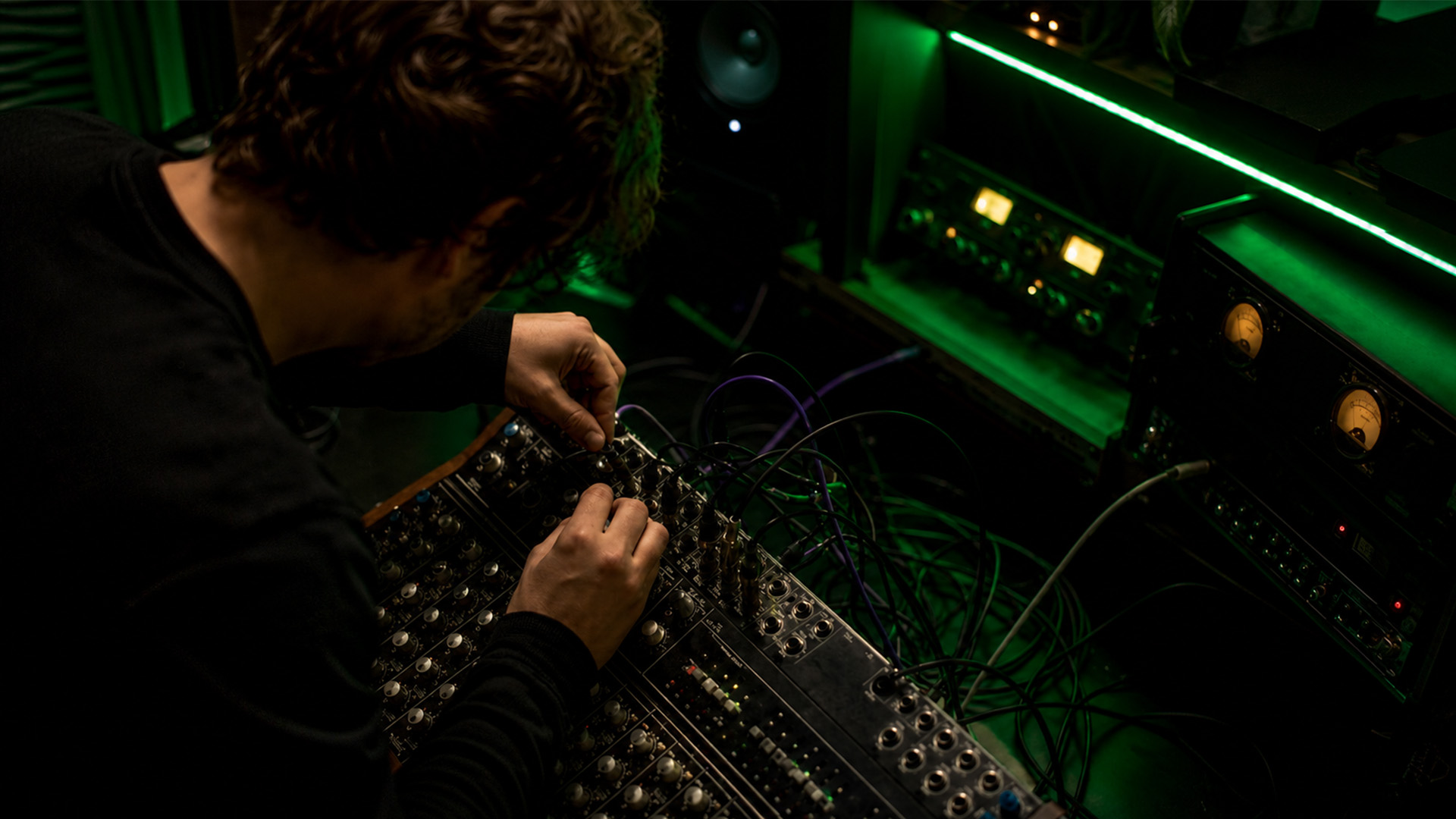 Hands connecting audio cables in a music studio