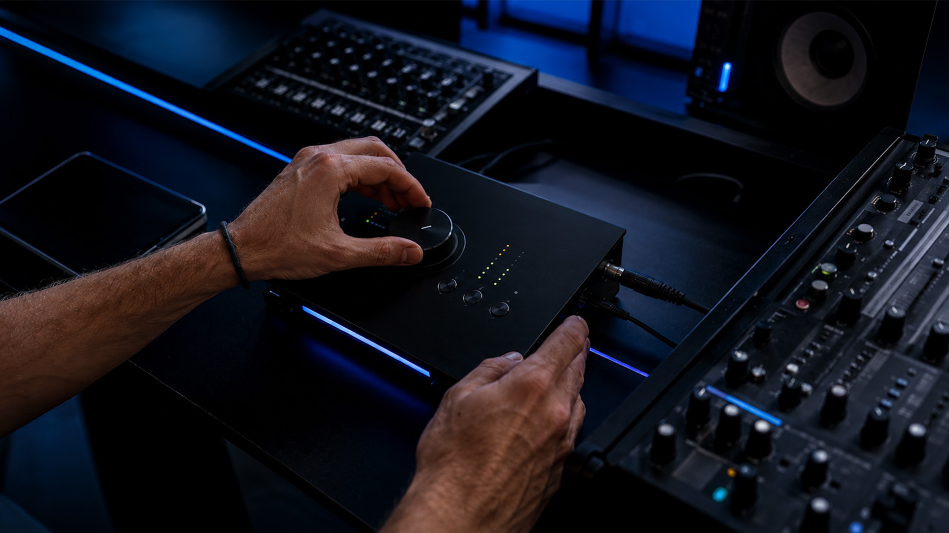 Hands adjusting an audio interface's knob in a modern studio