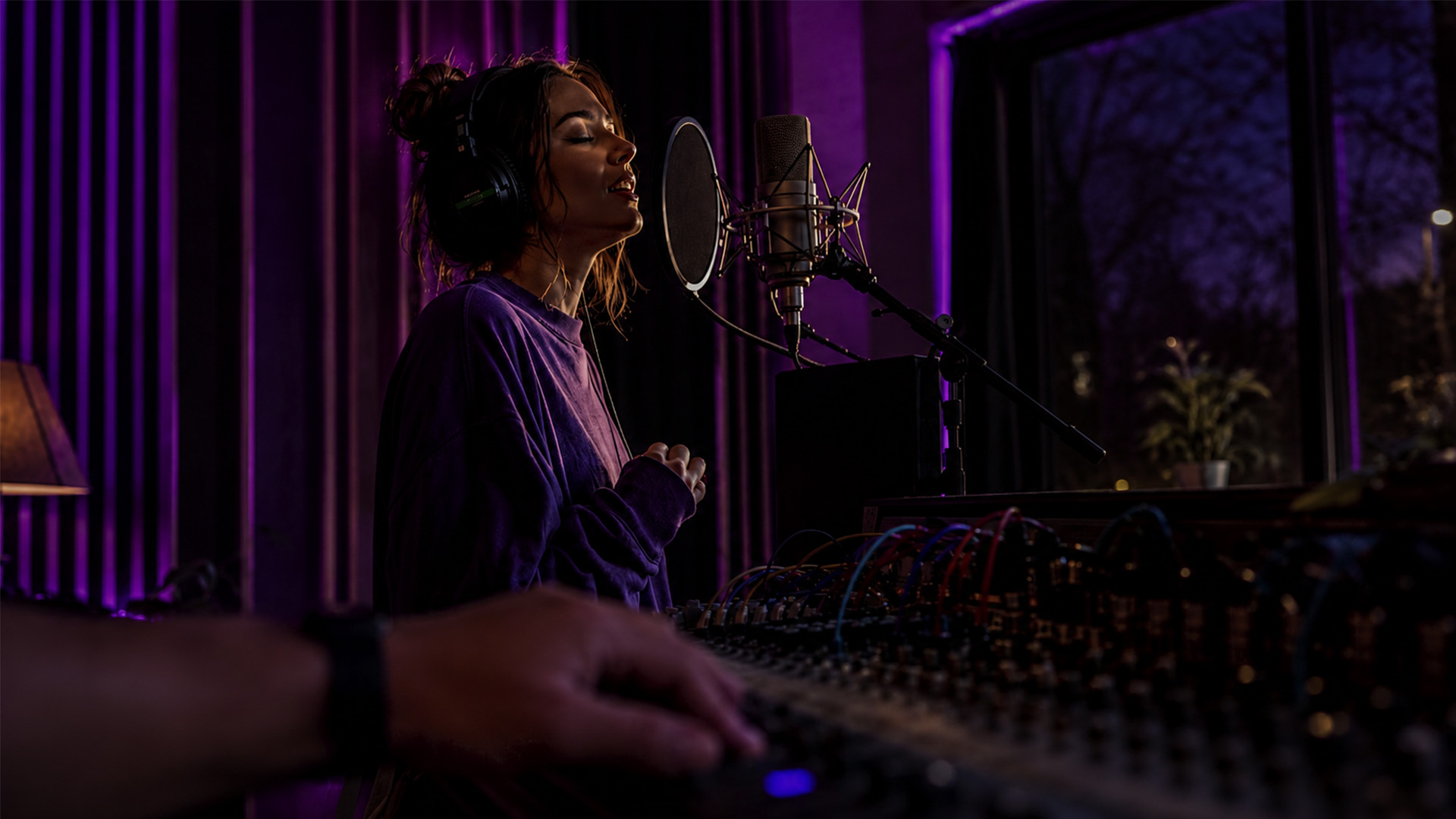 Close-up hands on a mixing console during a real-time vocal tracking session