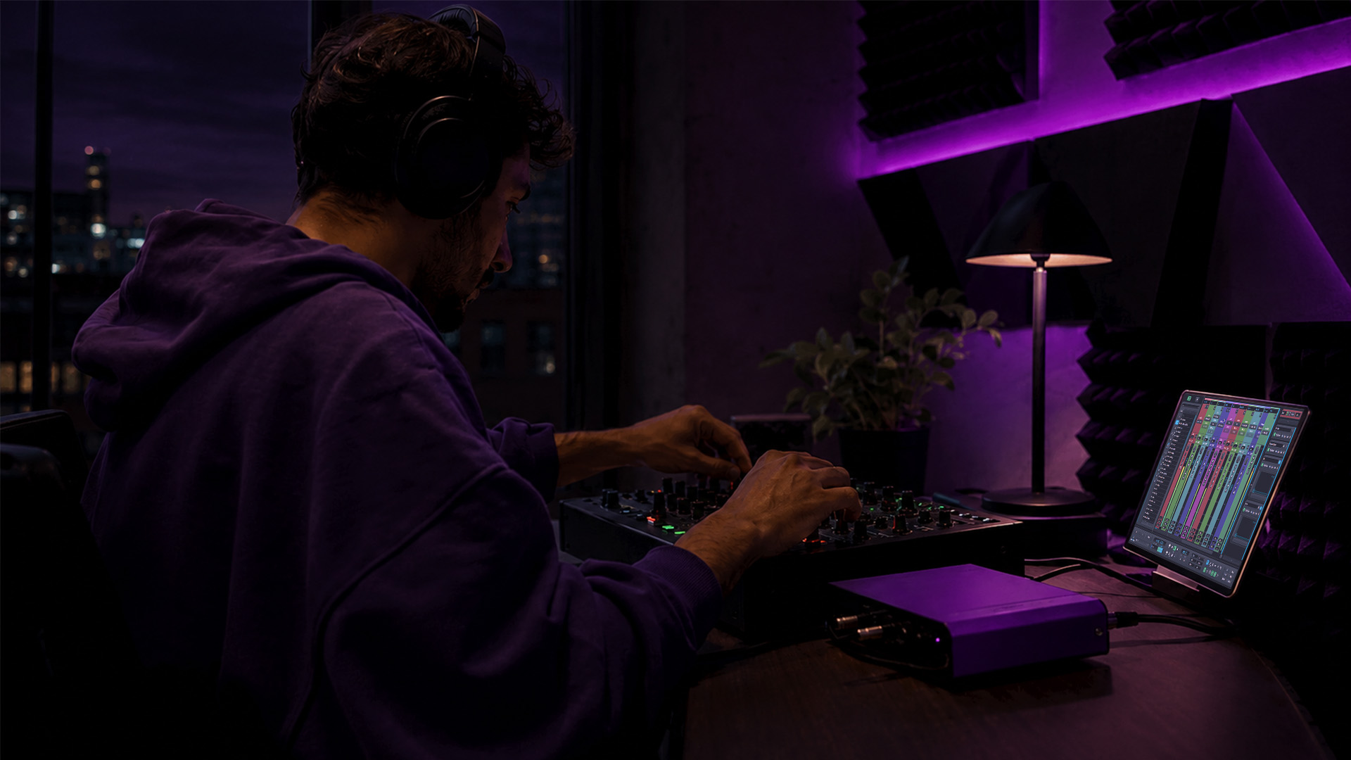 A producer adjusting an audio mixer in a home studio